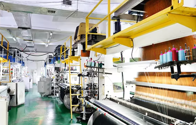 Woven-label production equipment with yarn spools and weaving looms in the workshop