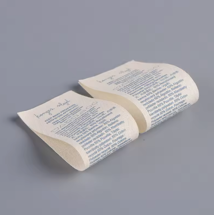 Two cream care label samples with blue text arranged in folded shapes on a grey background